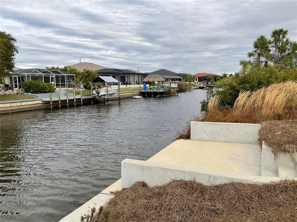 A concrete bulkhead and landing overlook a canal with boat docks and residential homes — 3431 NW 17TH LANE, CAPE CORAL, FL