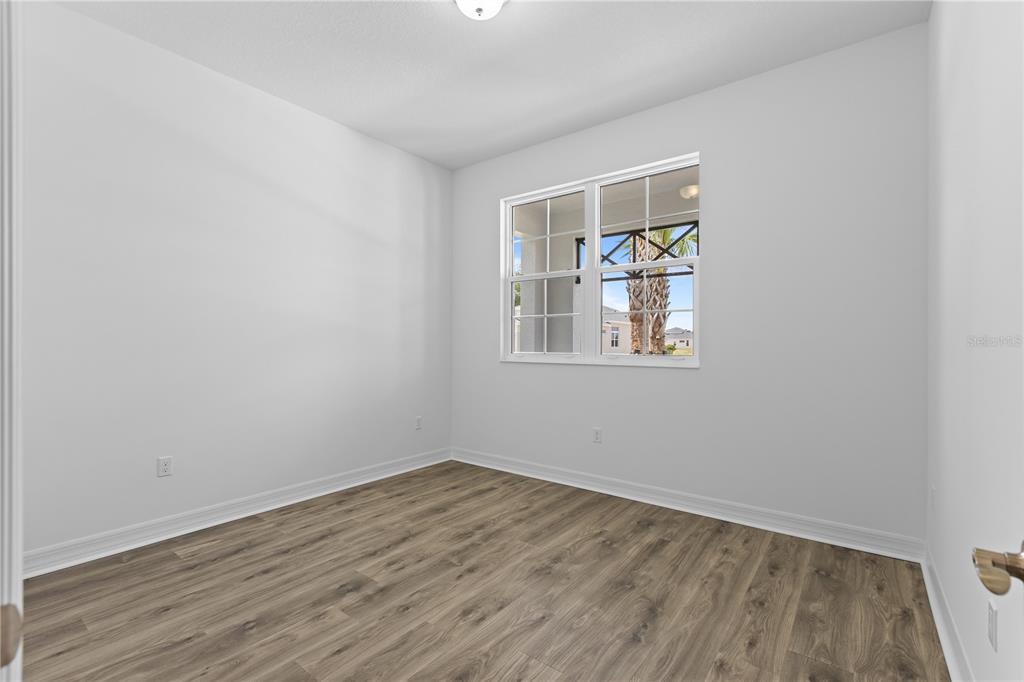 An empty room with white walls, wood-look flooring, and a window overlooking a neighborhood — 1068 LILIANA DRIVE, DELAND, FL