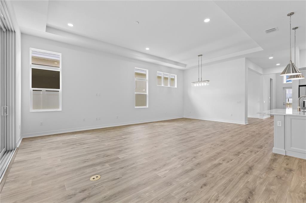 An open-concept living and dining area with light wood-look flooring and recessed ceiling lighting — 1068 LILIANA DRIVE, DELAND, FL
