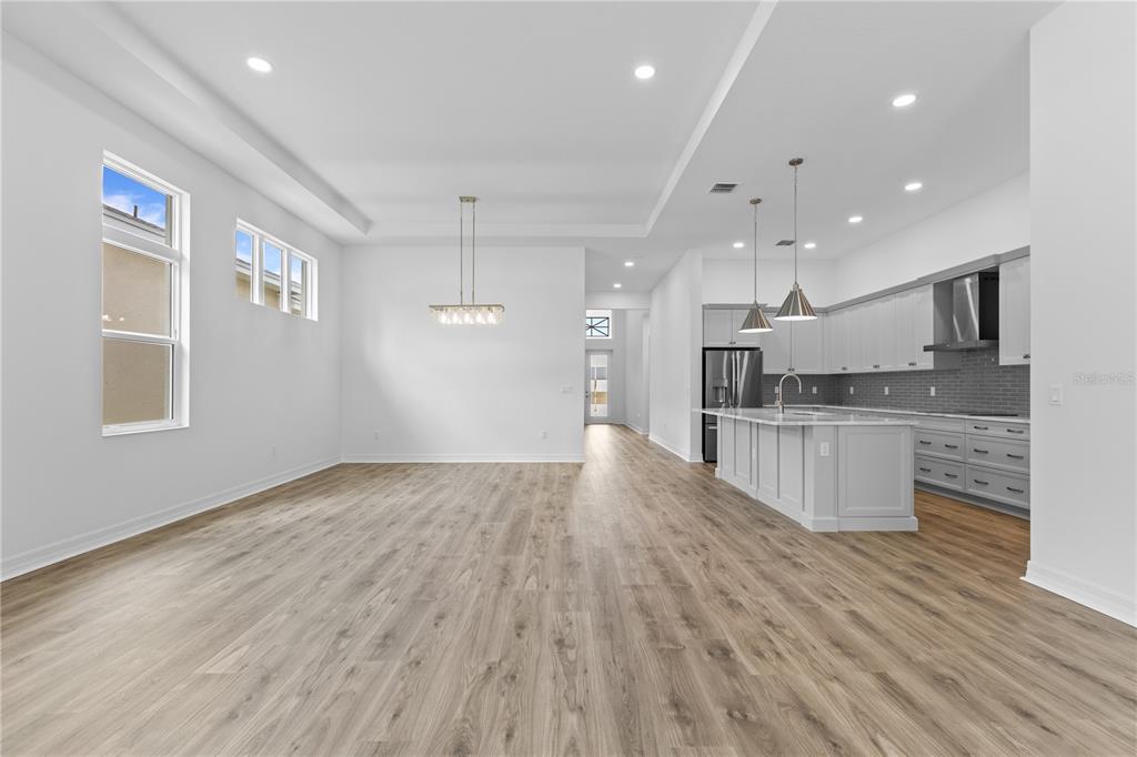 An open-concept kitchen and dining area features light wood flooring, white cabinetry, and recessed lighting — 1068 LILIANA DRIVE, DELAND, FL