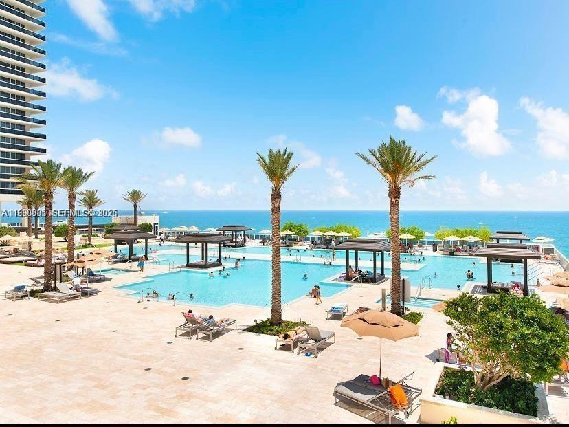A large swimming pool area features multiple cabanas, palm trees, and ocean views — 1830 S Ocean Dr # 2011, Hallandale Beach FL 33009, HALLANDALE BEACH, FL
