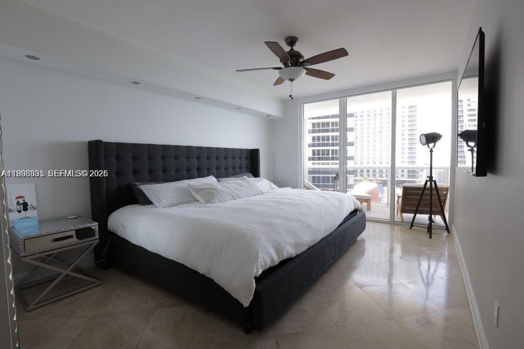 A bedroom features a large dark upholstered bed, white bedding, tile floors, and a balcony view — 1830 S Ocean Dr # 2011, Hallandale Beach FL 33009, HALLANDALE BEACH, FL