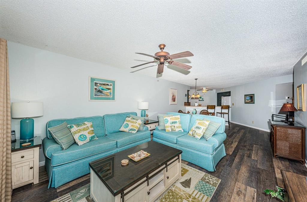 A living room features two turquoise sofas, a coffee table, and dark wood-look flooring — 6100 BAHIA DEL MAR CIRCLE UNIT 103, ST PETERSBURG, FL