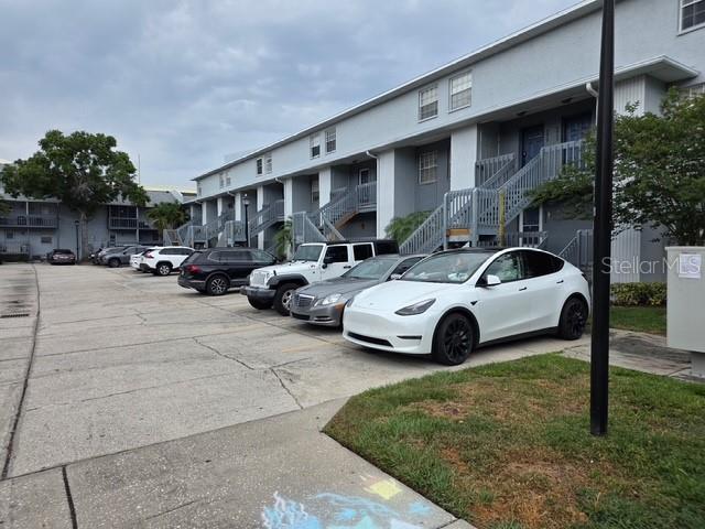 A white Tesla is parked in front of a multi-story apartment building with exterior staircases — 4821 W MCELROY AVENUE UNIT D210, TAMPA, FL