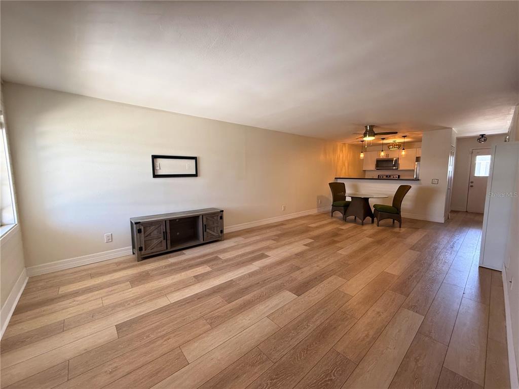 An open-concept living and dining area features light wood-look flooring and a kitchen breakfast bar — 4821 W MCELROY AVENUE UNIT D210, TAMPA, FL