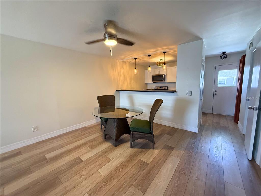 A dining area with a glass table and two chairs sits before an open kitchen — 4821 W MCELROY AVENUE UNIT D210, TAMPA, FL