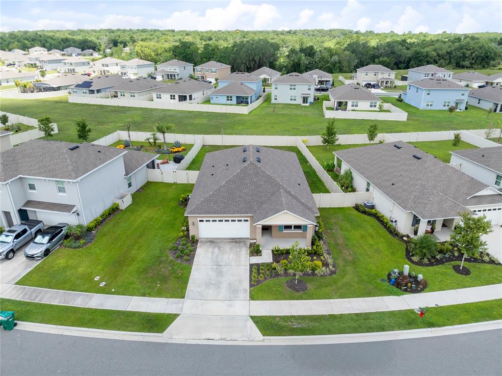 An aerial view shows a suburban house with a gray roof and driveway — 5207 MAHOGANY DRIVE, MOUNT DORA, FL