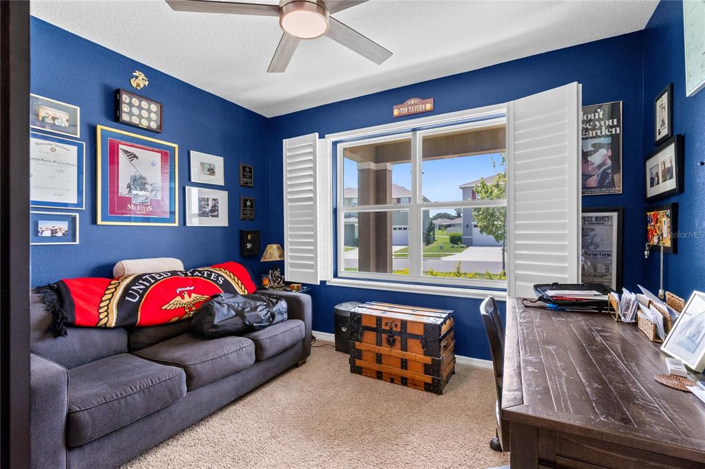 A home office with blue walls, a gray sofa, a wooden desk, and a window — 5207 MAHOGANY DRIVE, MOUNT DORA, FL