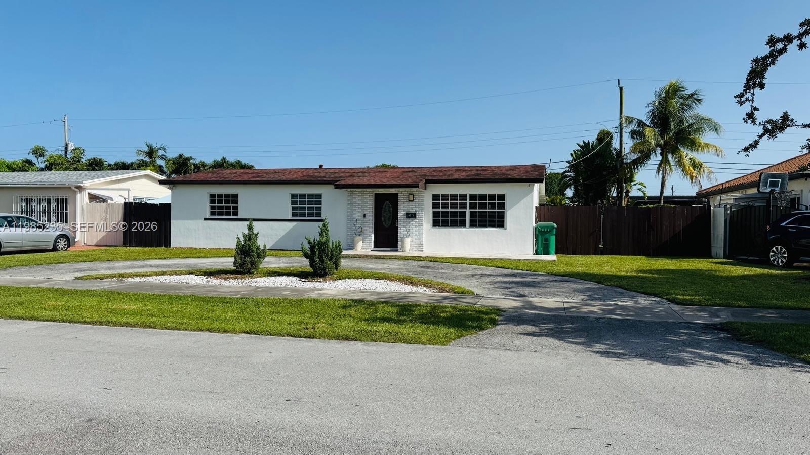 A single-story white house with a dark roof and a circular driveway sits on grass — 9770 SW 13th Ter, Miami FL 33174, MIAMI, FL