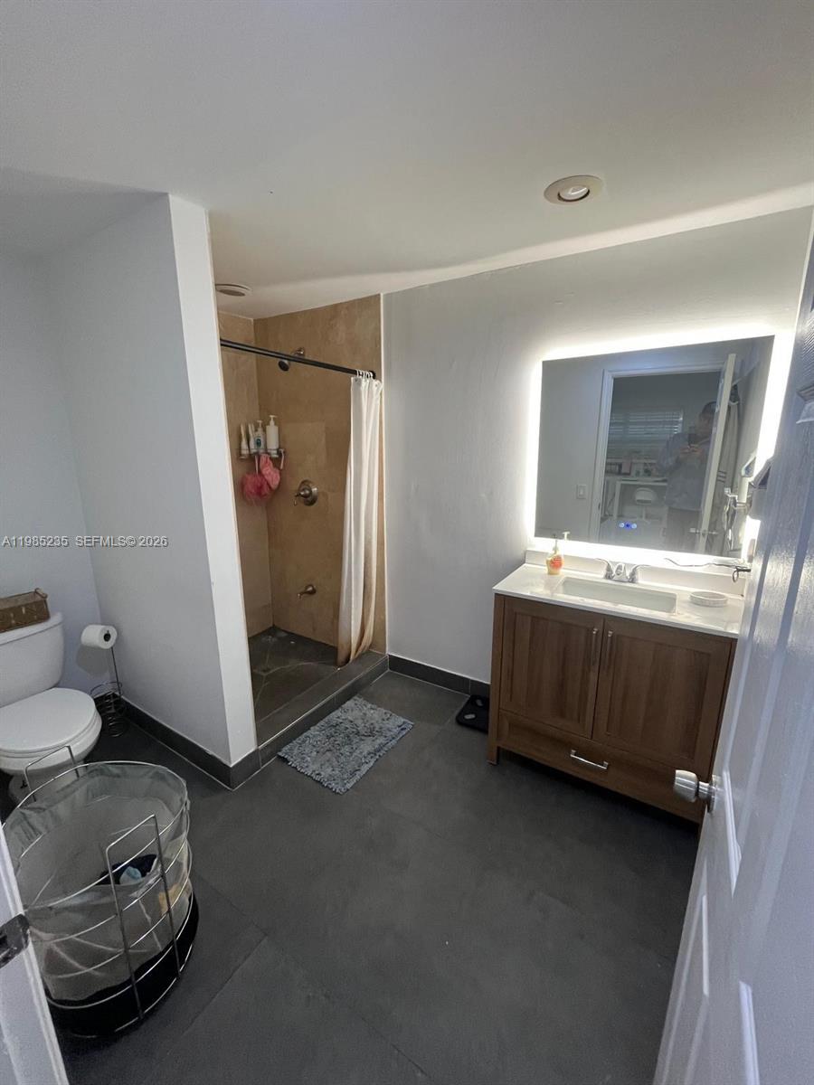 A bathroom features a walk-in shower, a wooden vanity with a backlit mirror, and tile flooring — 9770 SW 13th Ter, Miami FL 33174, MIAMI, FL