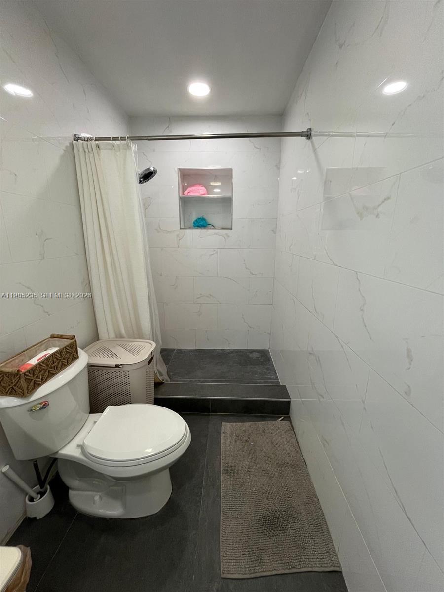 A bathroom features a walk-in shower with white marble-look tiles and a dark floor — 9770 SW 13th Ter, Miami FL 33174, MIAMI, FL