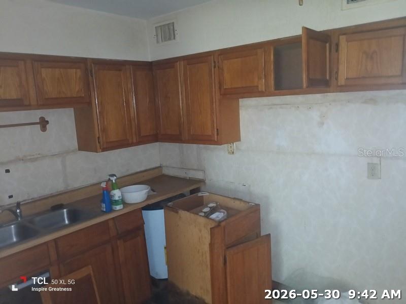 A kitchen features wooden cabinets, a stainless steel sink, and unfinished walls — 1114 30TH STREET NW, WINTER HAVEN, FL