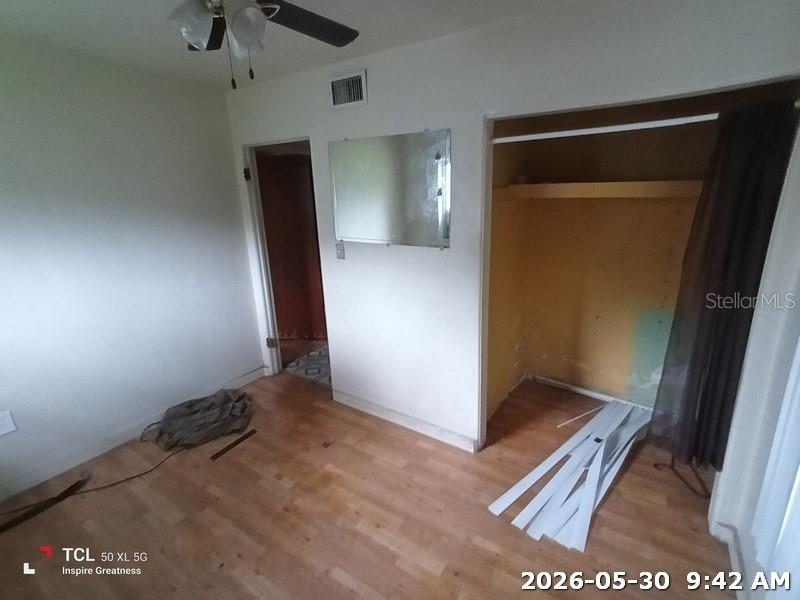 A bedroom features light wood flooring, a ceiling fan, a mirror, and an open closet — 1114 30TH STREET NW, WINTER HAVEN, FL