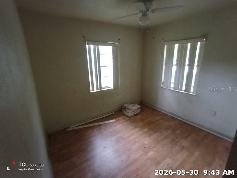 An empty bedroom features light-colored walls, wood-look flooring, two windows with blinds, and a ceiling fan — 1114 30TH STREET NW, WINTER HAVEN, FL