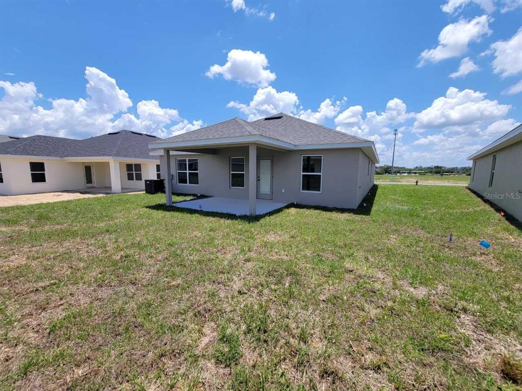 The rear exterior of a single-story house features a covered patio and a grassy yard — 4386 SW 92ND PLACE ROAD, OCALA, FL