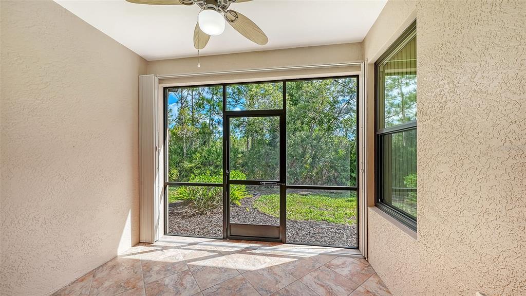 A covered patio features tiled flooring, a sliding glass door, and a single window — 1821 BATELLO DRIVE, VENICE, FL