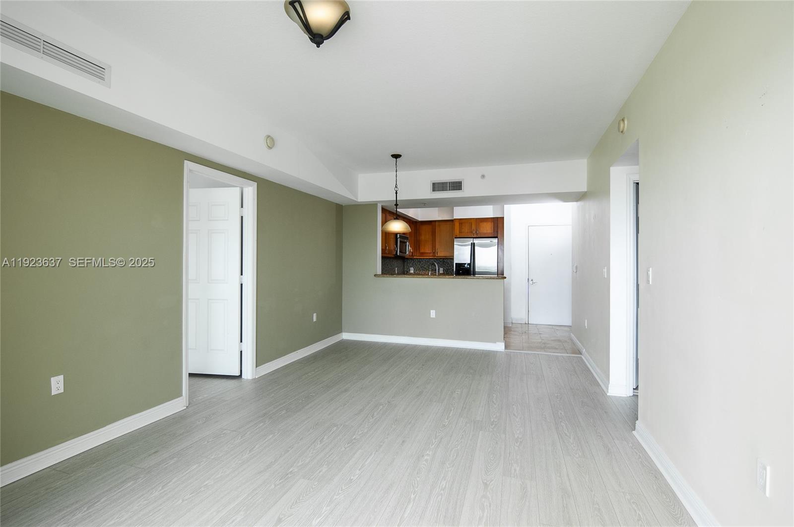 An open living area features light wood-look flooring, sage green walls, and a kitchen pass-through — 1745 E Hallandale Beach Blvd # 1508W, Hallandale Beach FL 33009, HALLANDALE BEACH, FL