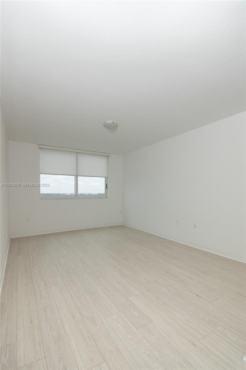 An empty room features light-colored wood-look flooring, white walls, and a window with blinds — 1745 E Hallandale Beach Blvd # 1508W, Hallandale Beach FL 33009, HALLANDALE BEACH, FL