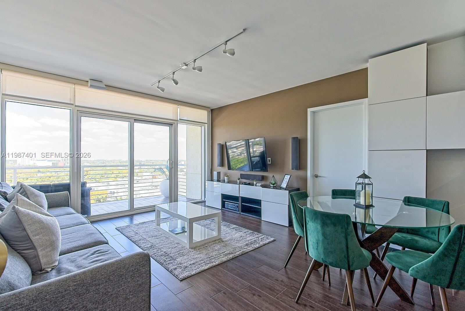 A modern living and dining area features a gray sofa, glass table, and balcony view — 3250 NE 1st Ave # 1006, Miami FL 33137, MIAMI, FL