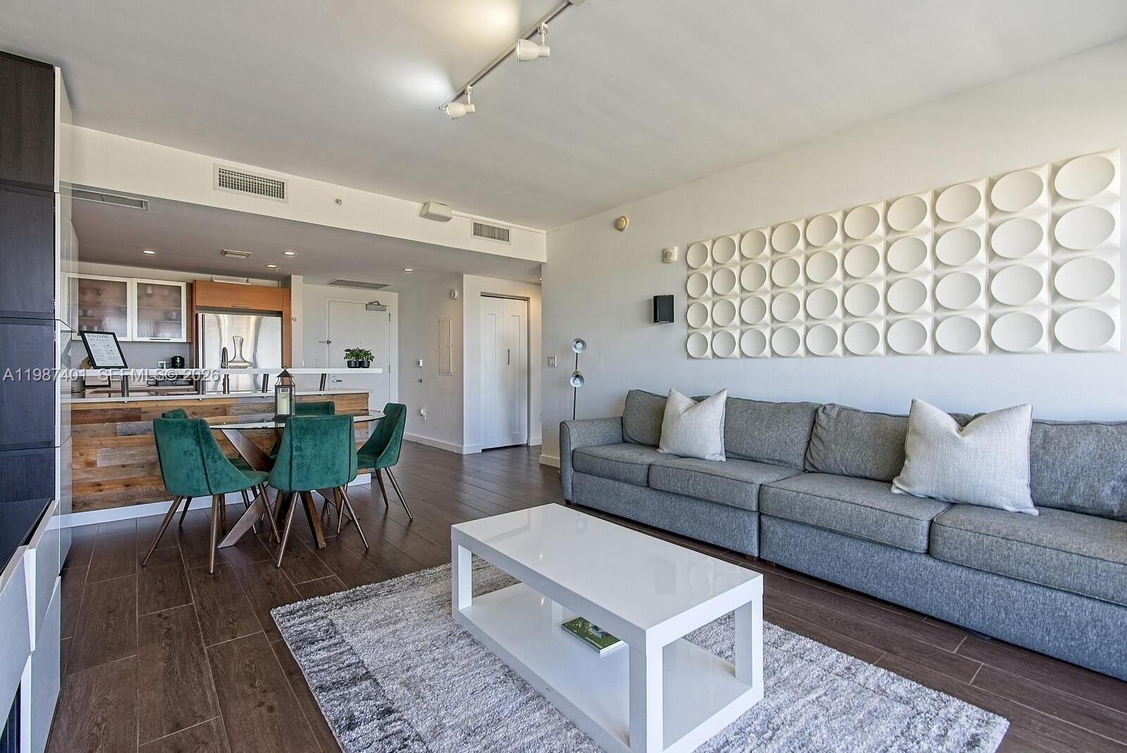 A modern living room features a grey sofa, white coffee table, and green dining chairs — 3250 NE 1st Ave # 1006, Miami FL 33137, MIAMI, FL
