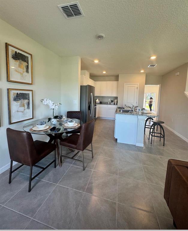 An open-concept kitchen features white cabinetry, a central island, and an adjacent dining area — 416 PRESTON COVE DRIVE, ST CLOUD, FL