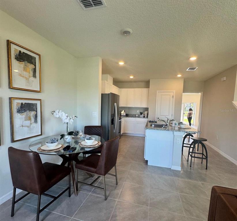 A dining area with a glass table and chairs sits adjacent to a white kitchen — 416 PRESTON COVE DRIVE, ST CLOUD, FL