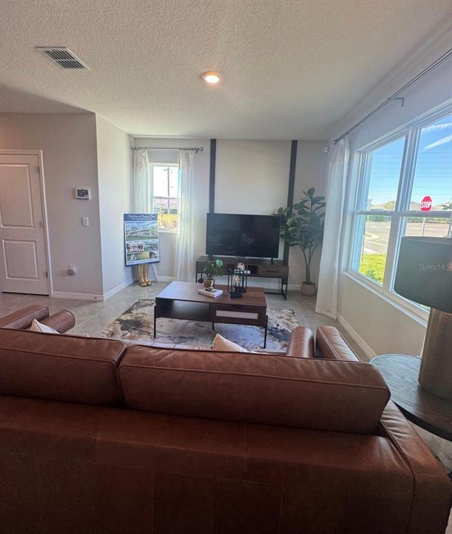 A living room features a brown leather sofa, a television on a stand, and windows — 416 PRESTON COVE DRIVE, ST CLOUD, FL