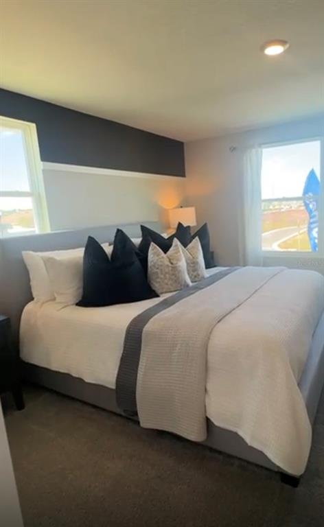 A bedroom features a gray upholstered bed with dark pillows and a two-toned wall — 416 PRESTON COVE DRIVE, ST CLOUD, FL