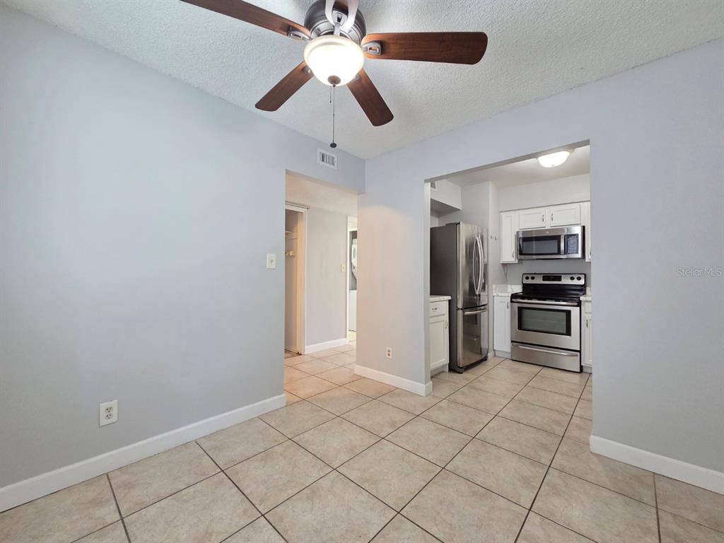 A dining area with tile flooring and a ceiling fan opens into a stainless steel kitchen — 3004 GEORGE MASON AVENUE UNIT K5, WINTER PARK, FL