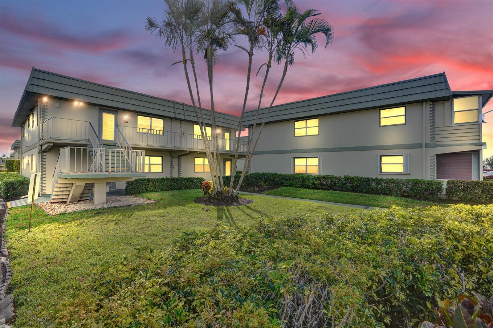 A two-story apartment building with a central palm tree and a sunset sky background — 505 Monaco K, Delray Beach FL 33446, DELRAY BEACH, FL