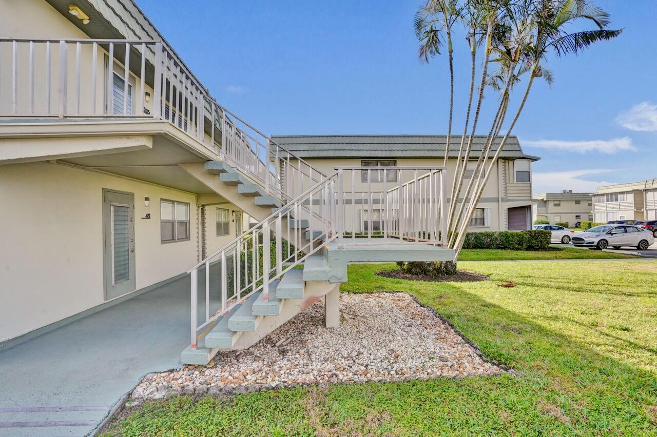 An exterior view of a two-story apartment building featuring an outdoor concrete staircase and walkway — 505 Monaco K, Delray Beach FL 33446, DELRAY BEACH, FL