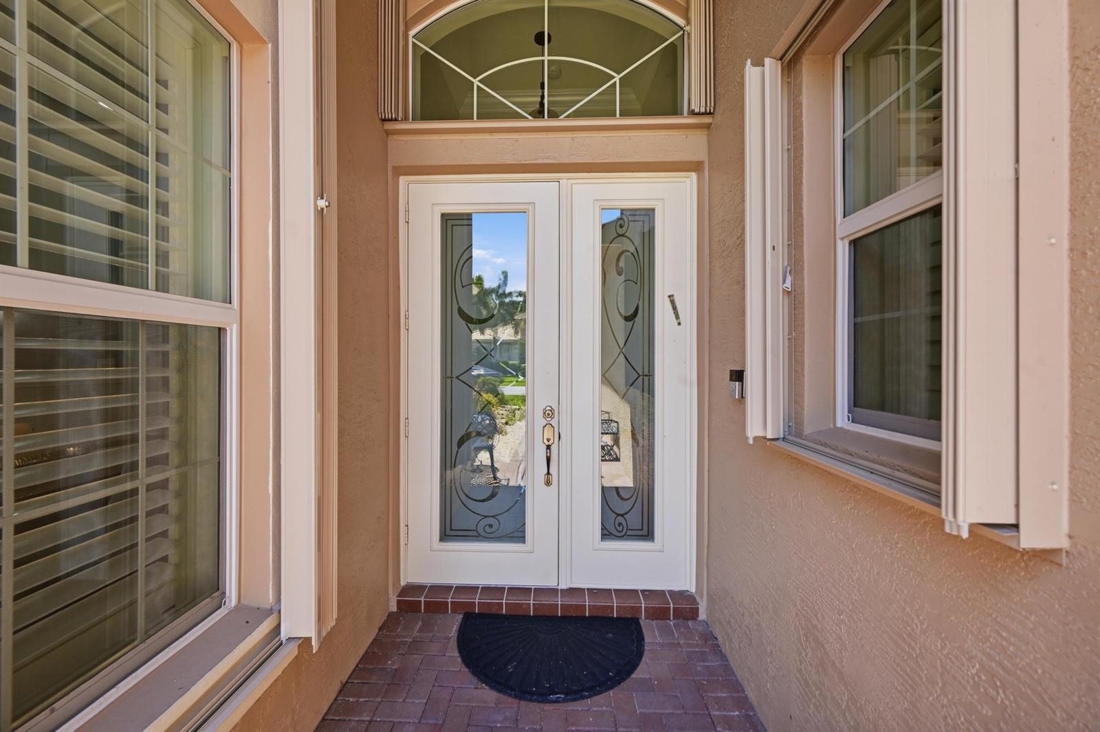 A front entryway features a double glass-paneled door, a brick floor, and a transom window — 10469 Whitewind Circle, Boynton Beach FL 33473, BOYNTON BEACH, FL