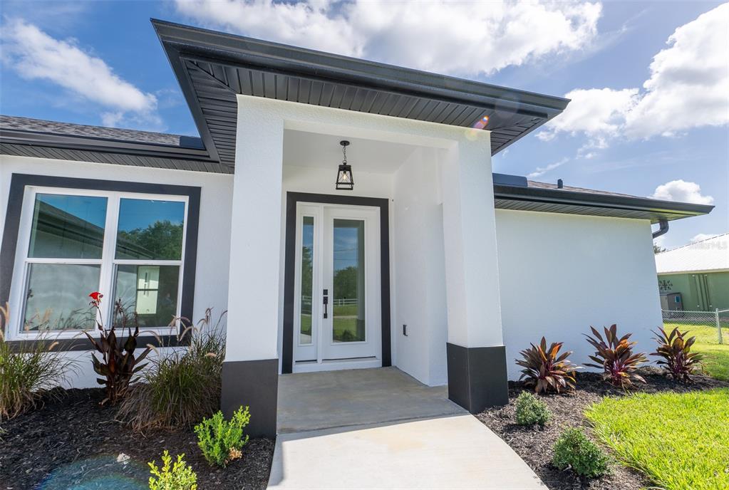 A modern white house exterior features a dark-trimmed front door and a covered entryway — 8846 SW LIVERPOOL ROAD, ARCADIA, FL
