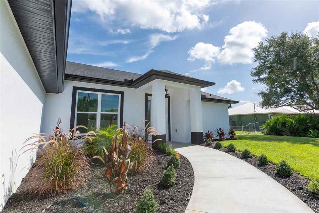 A white house exterior features a concrete walkway leading to a covered front entrance — 8846 SW LIVERPOOL ROAD, ARCADIA, FL