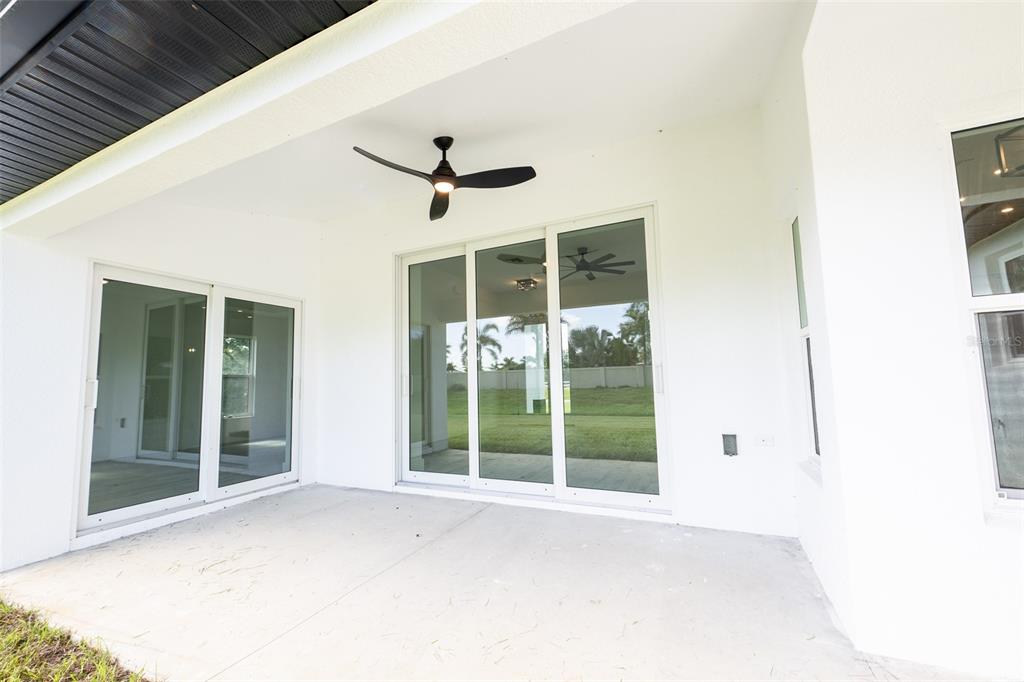 A covered concrete patio features white walls, a ceiling fan, and sliding glass doors — 8846 SW LIVERPOOL ROAD, ARCADIA, FL