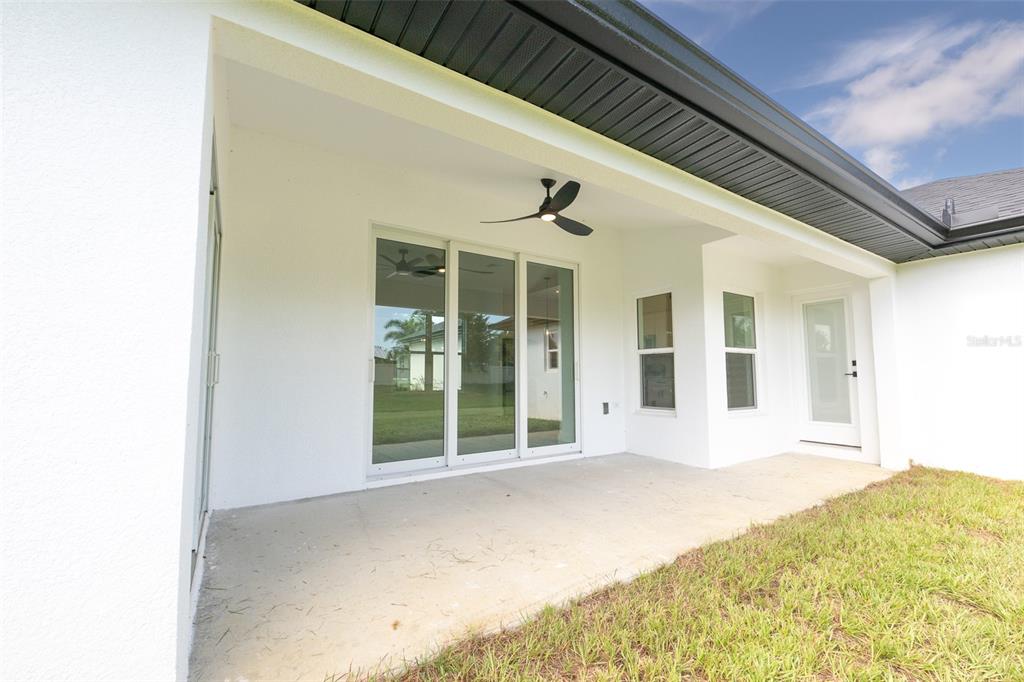A covered concrete patio features a ceiling fan, sliding glass doors, and a white exterior — 8846 SW LIVERPOOL ROAD, ARCADIA, FL
