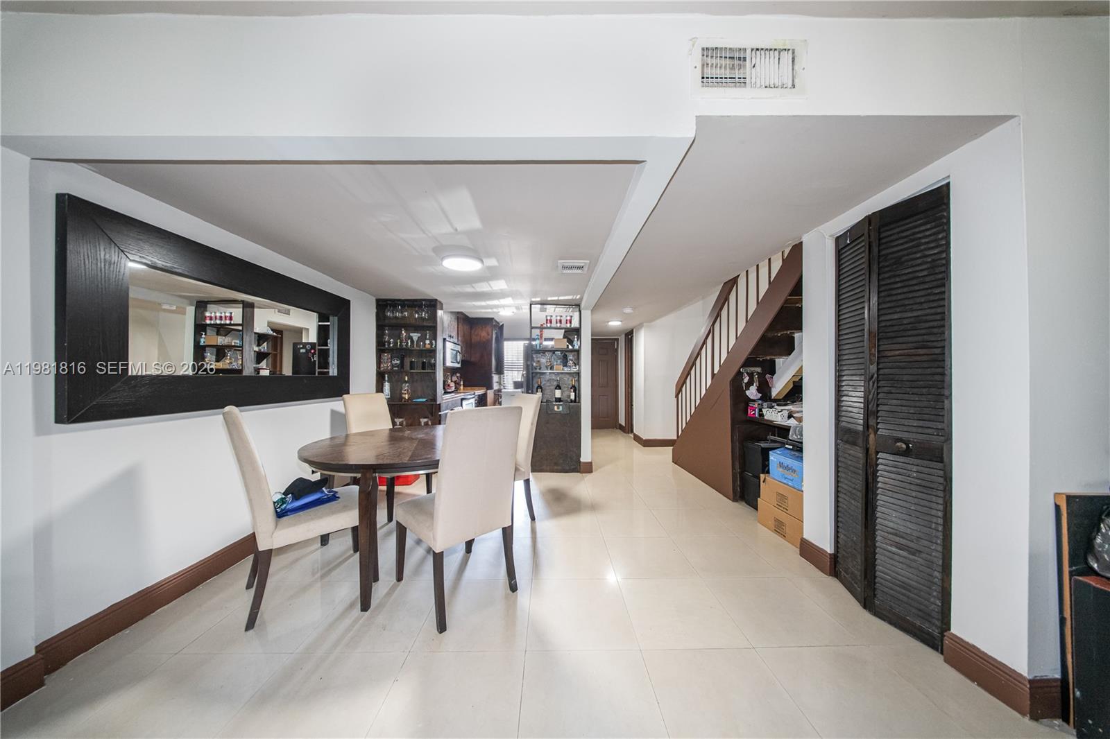 A dining area features a wooden table, four chairs, a large mirror, and a staircase — 10710 NW 7th St # 11B, Miami FL 33172, MIAMI, FL