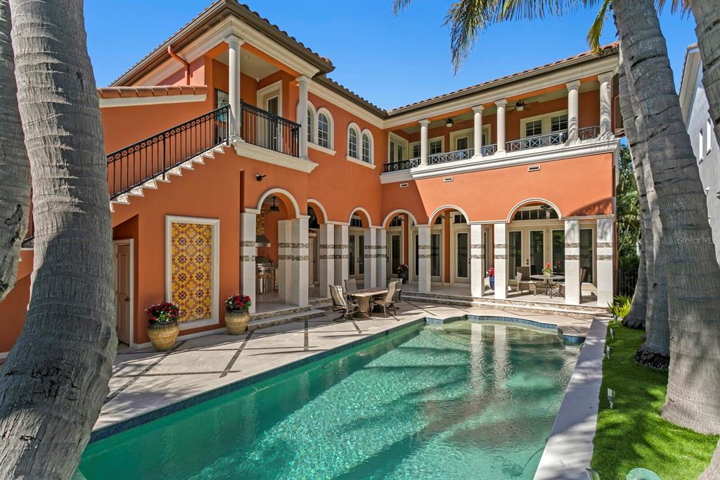 A two-story orange house with a pool, covered patio, and palm trees in the yard — 4912 YACHT CLUB DRIVE, TAMPA, FL