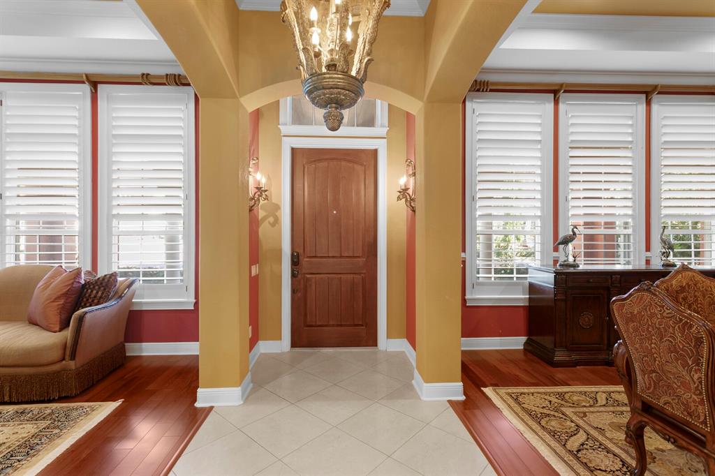 An entryway features a wooden door, tile flooring, an ornate chandelier, and red-painted walls — 4912 YACHT CLUB DRIVE, TAMPA, FL