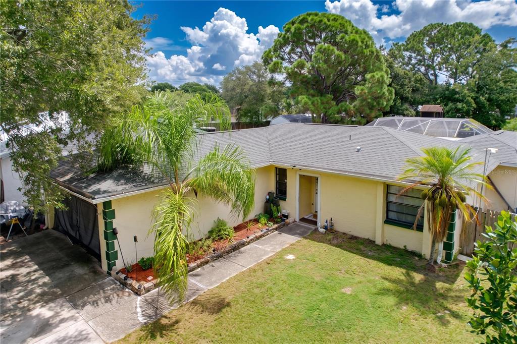 An exterior view of a single-story yellow house with a palm tree and front lawn — 6250 CEDARBROOK DRIVE N, PINELLAS PARK, FL
