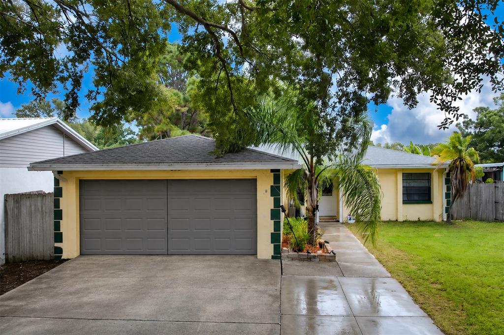 A single-story yellow house with a two-car garage, a palm tree, and a concrete driveway — 6250 CEDARBROOK DRIVE N, PINELLAS PARK, FL