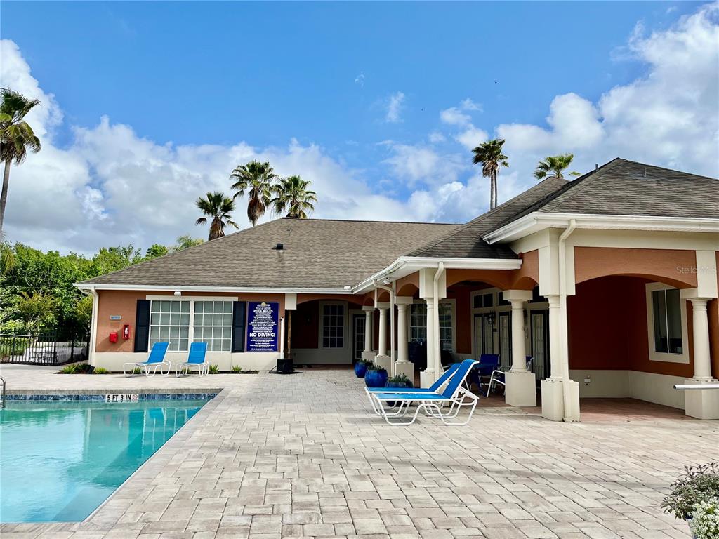 A swimming pool sits on a paved patio next to a building with a covered porch — 1939 SUMMER CLUB APT DRIVE UNIT 315, OVIEDO, FL