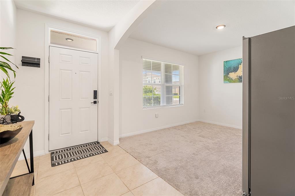 An entryway with tile flooring leads to a carpeted living area with a window — 2533 HARMONIA HAMMOCK ROAD, HARMONY, FL