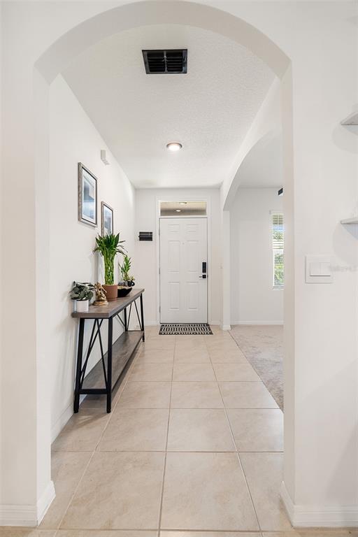 An entryway features a white front door, tiled flooring, and a console table with plants — 2533 HARMONIA HAMMOCK ROAD, HARMONY, FL