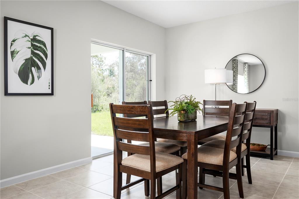 A dining room features a dark wood table with four chairs, tile flooring, and sliding doors — 17108 6TH TERRACE E, BRADENTON, FL