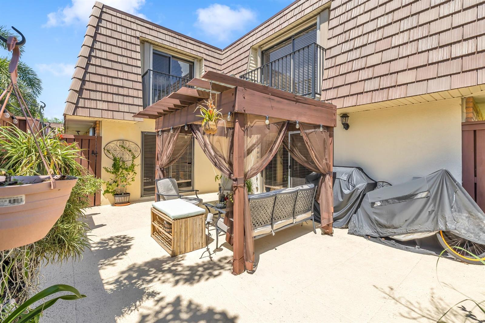A patio features a wooden pergola with curtains over outdoor seating and a covered grill — 2776 SW 15th Street, Deerfield Beach FL 33442, DEERFIELD BEACH, FL