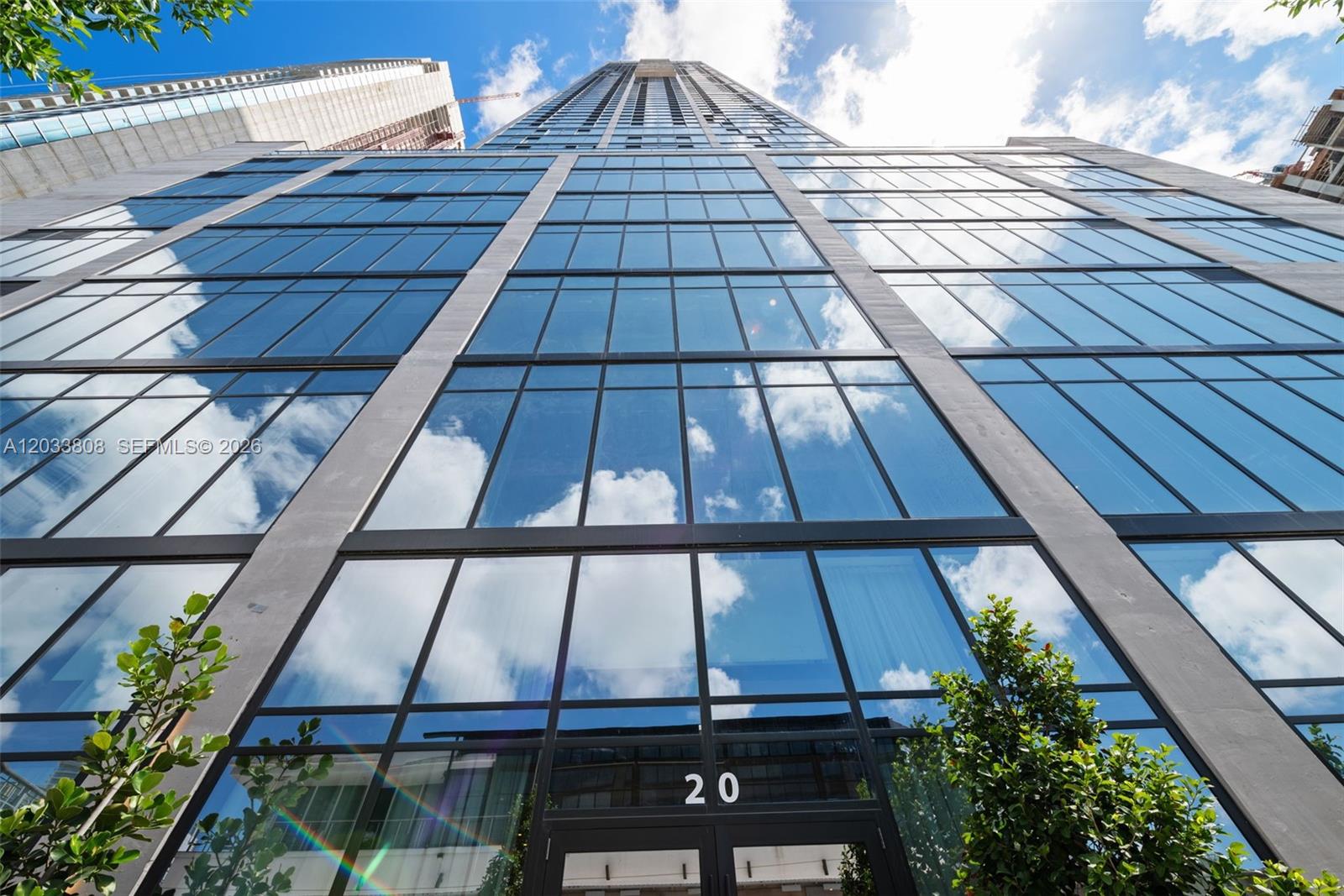 A low-angle view of a modern glass skyscraper with the number 20 above the entrance — 20 NE 11th Street # 4003B, Miami FL 33132, MIAMI, FL
