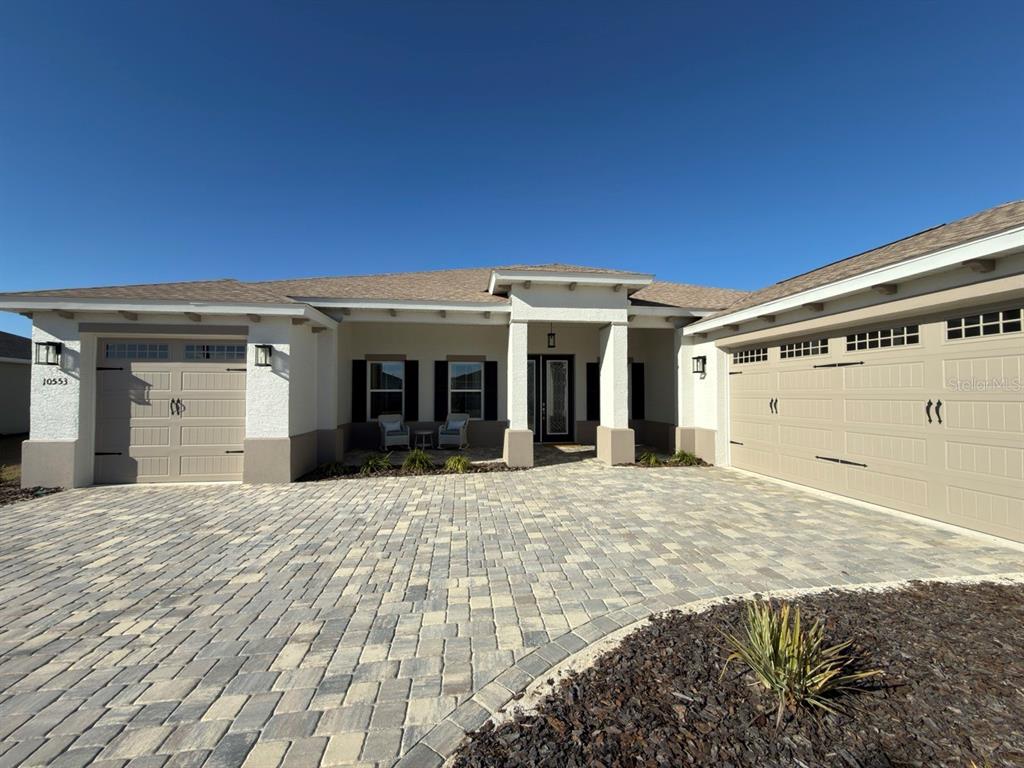 A single-story house exterior features a paved driveway, two garage doors, and a covered entryway — 10553 SW 98TH PLACE, OCALA, FL