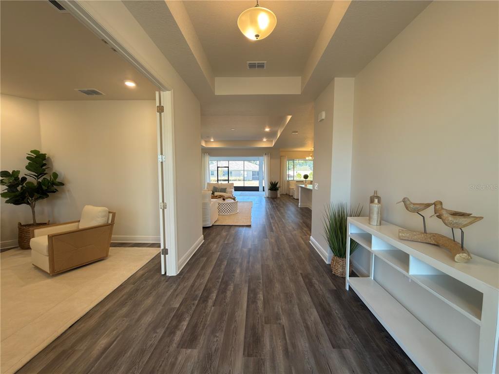 A view from a hallway looking into a living area with wood-look flooring — 10553 SW 98TH PLACE, OCALA, FL