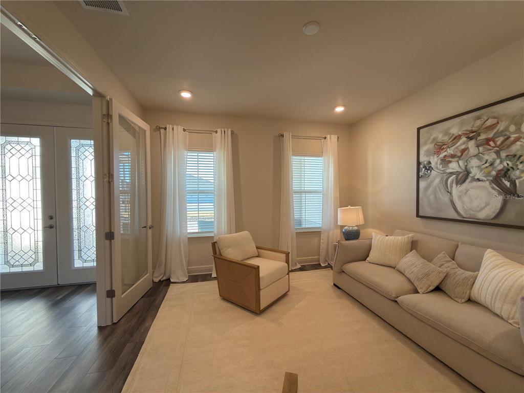 A living room features a beige sofa, an armchair, two windows, and a glass-paneled door — 10553 SW 98TH PLACE, OCALA, FL